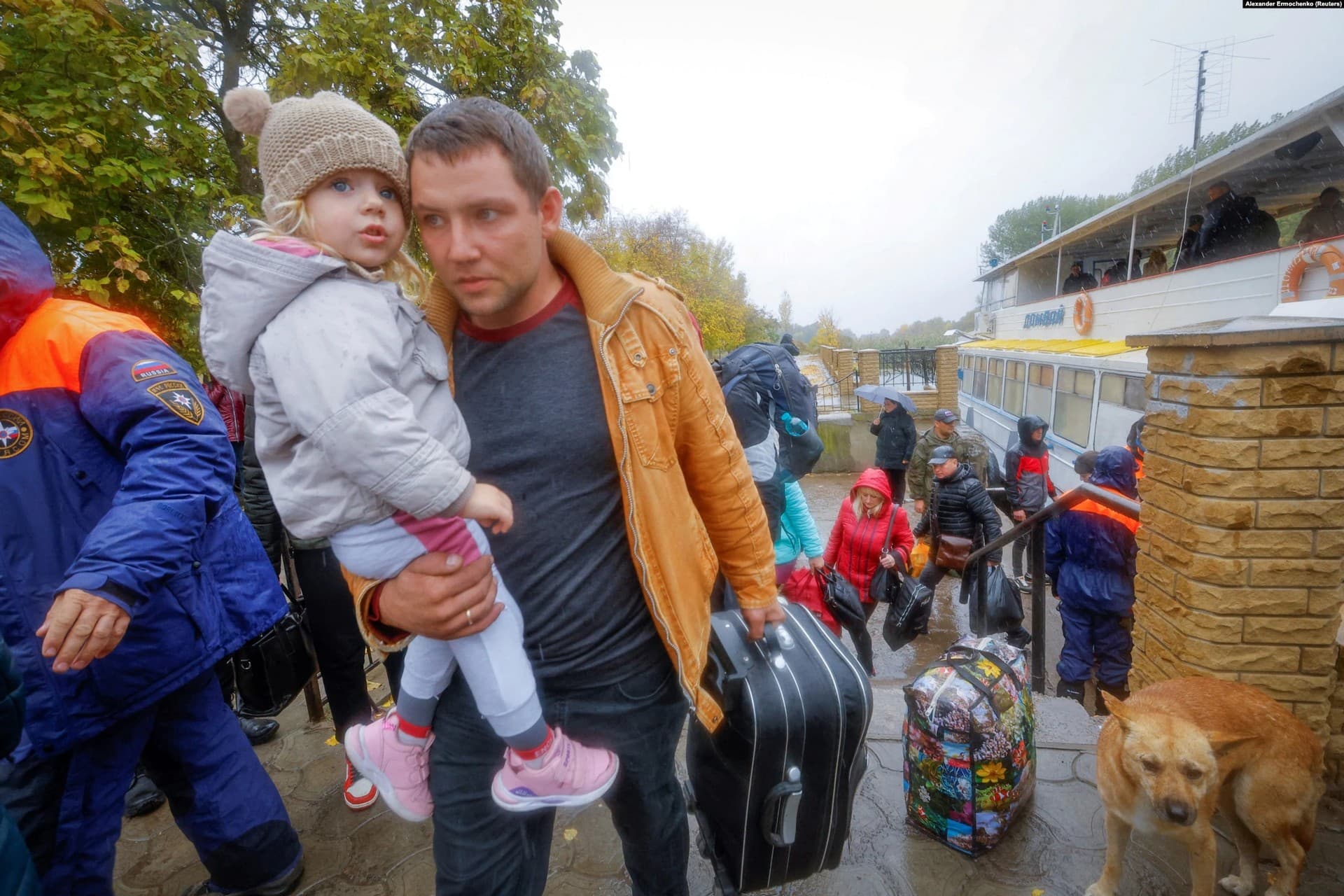 Civilians disembark a ferry and head toward transport that will take them to Russian-occupied Crimea in Oleshky