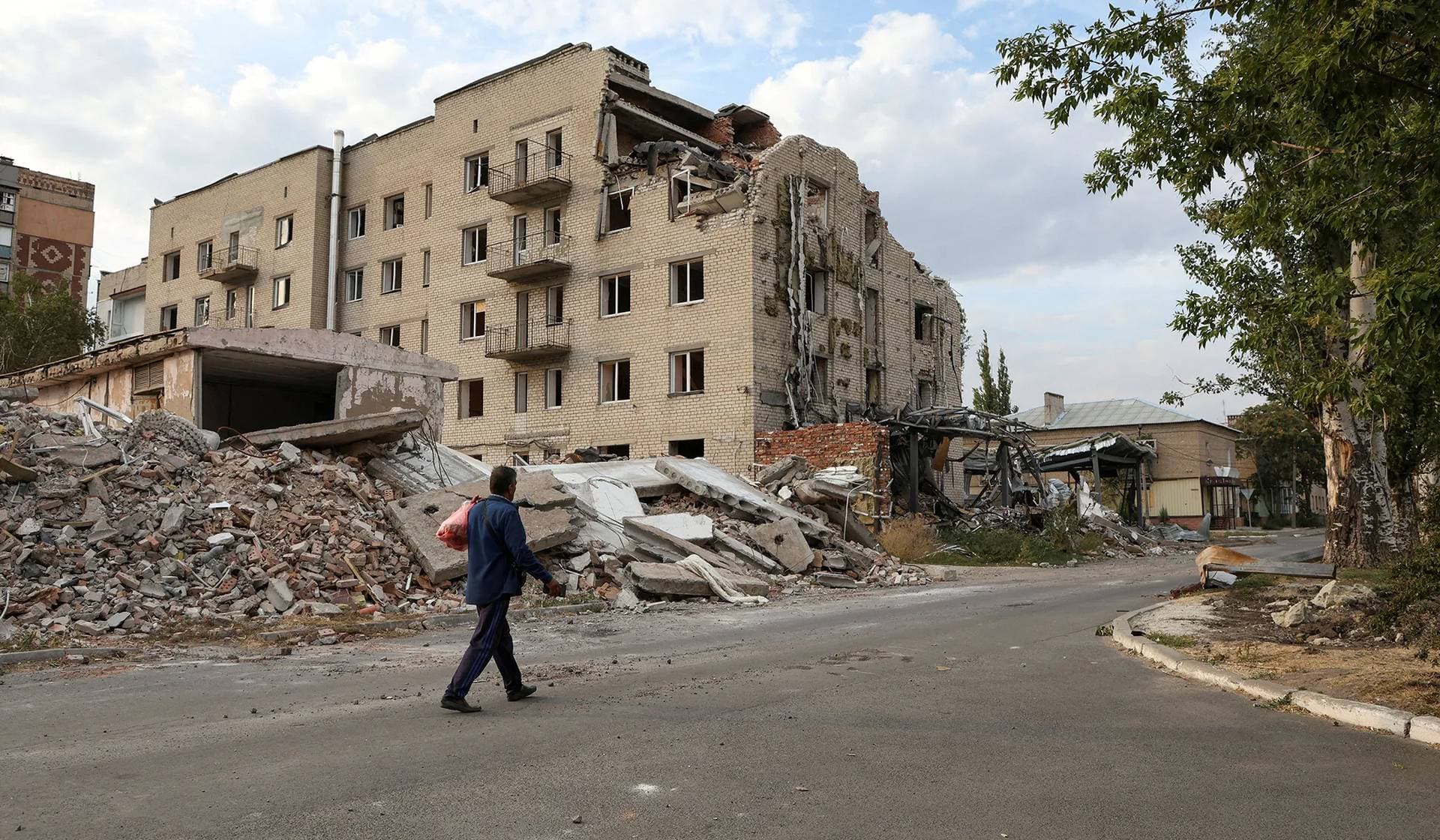 A man walks past a building damaged by a Russian military strike in Pokrovsk