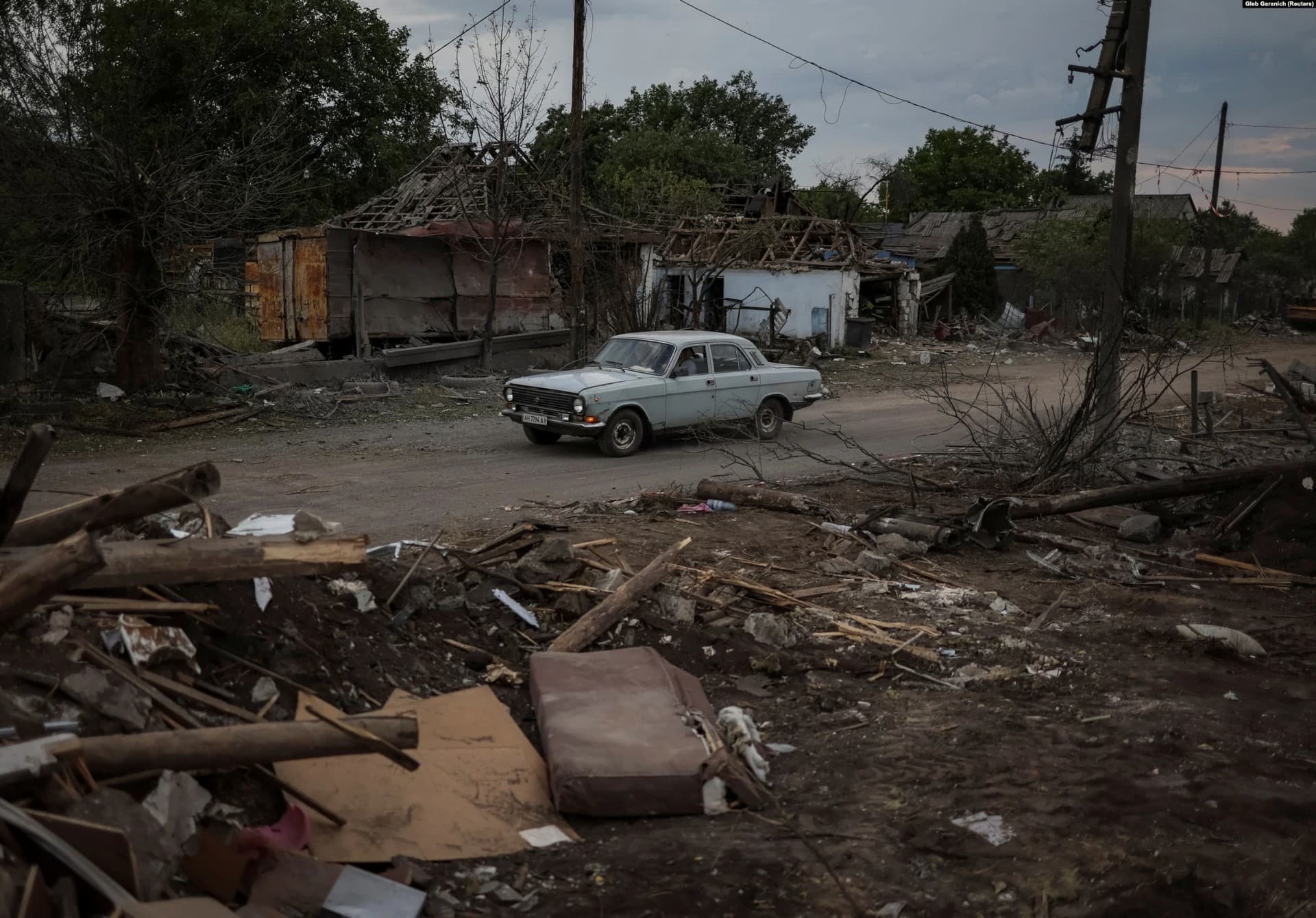 A car drives through the shattered settlement of Dobropillya that was struck by a Russian missile strike