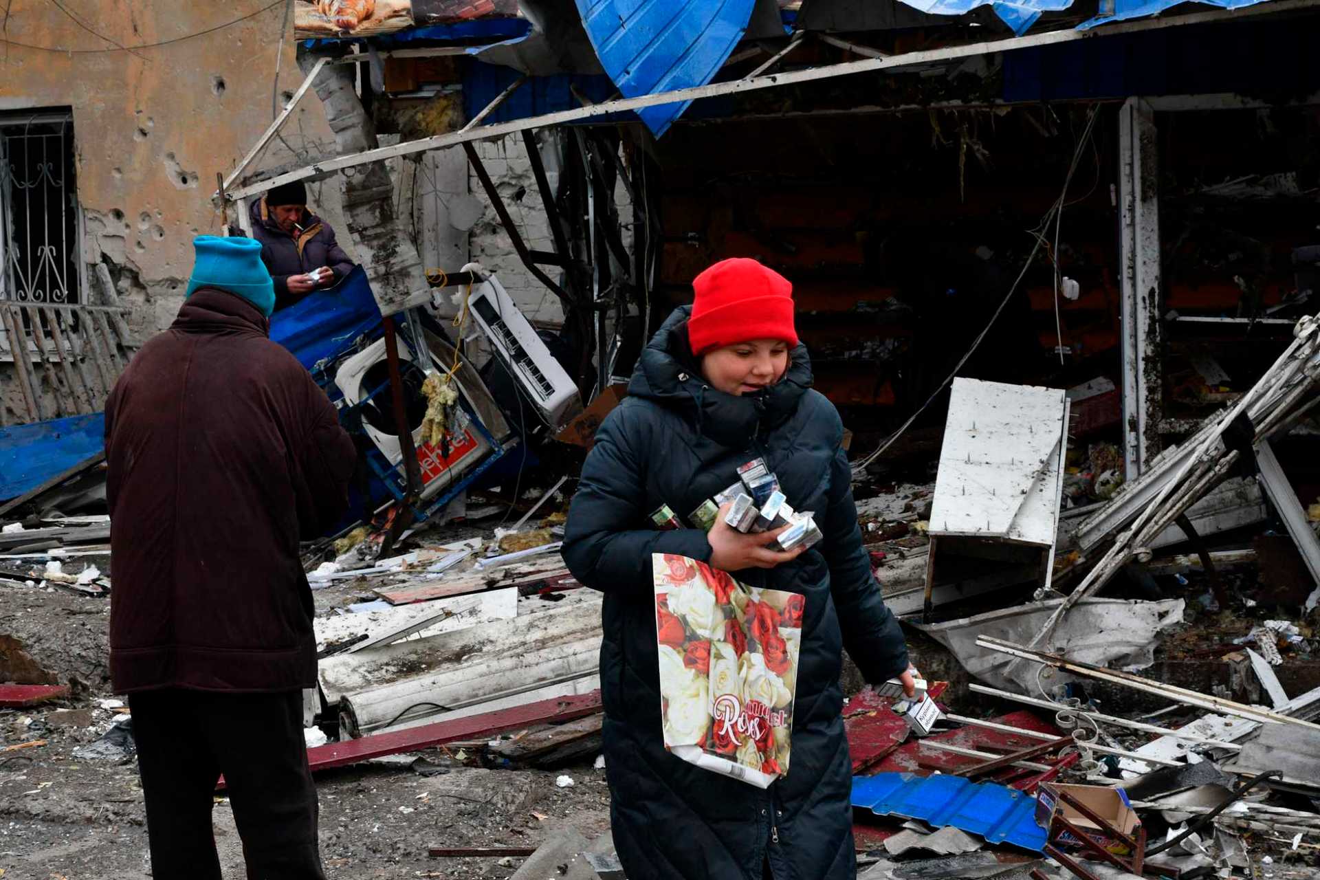 People take cigarettes from a ruined shop in a city market in Kurakhove