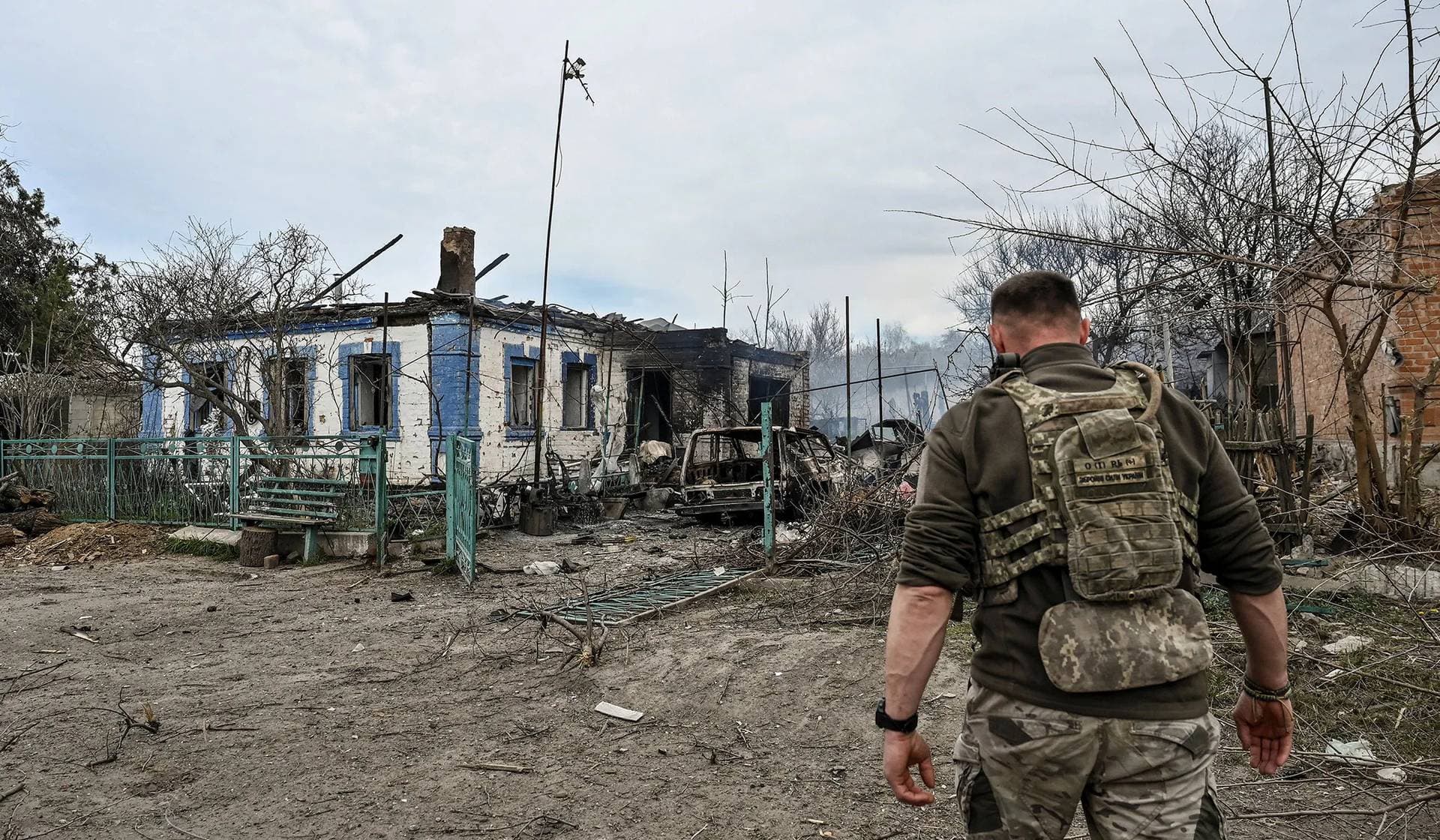 A Ukrainian service member walks in front of a residential building destroyed by a Russian air strike in the frontline town of Orikhiv
