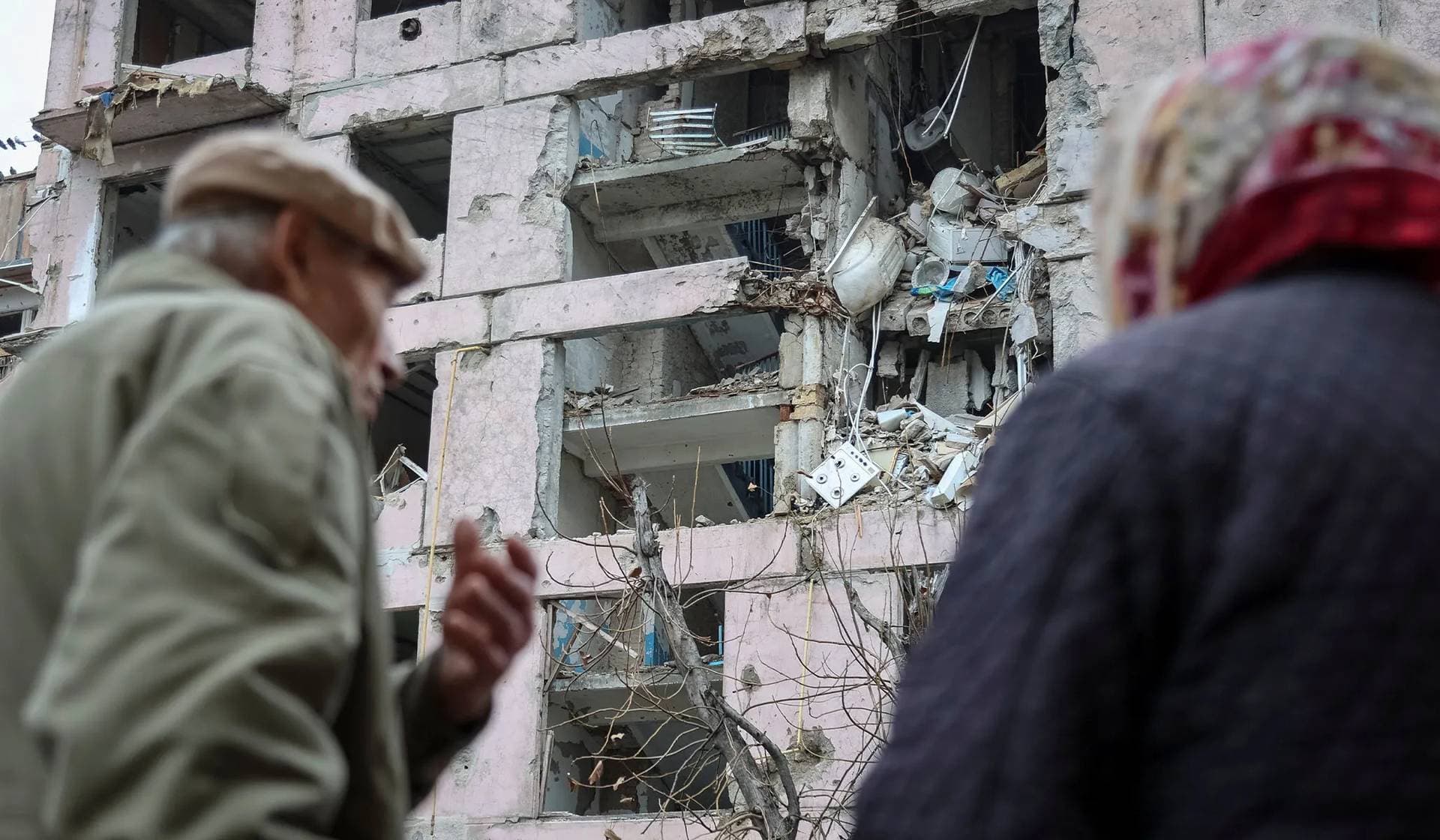 Residents stand near an apartment building hit during the Russian military strike, in the frontline town of Huliaipole
