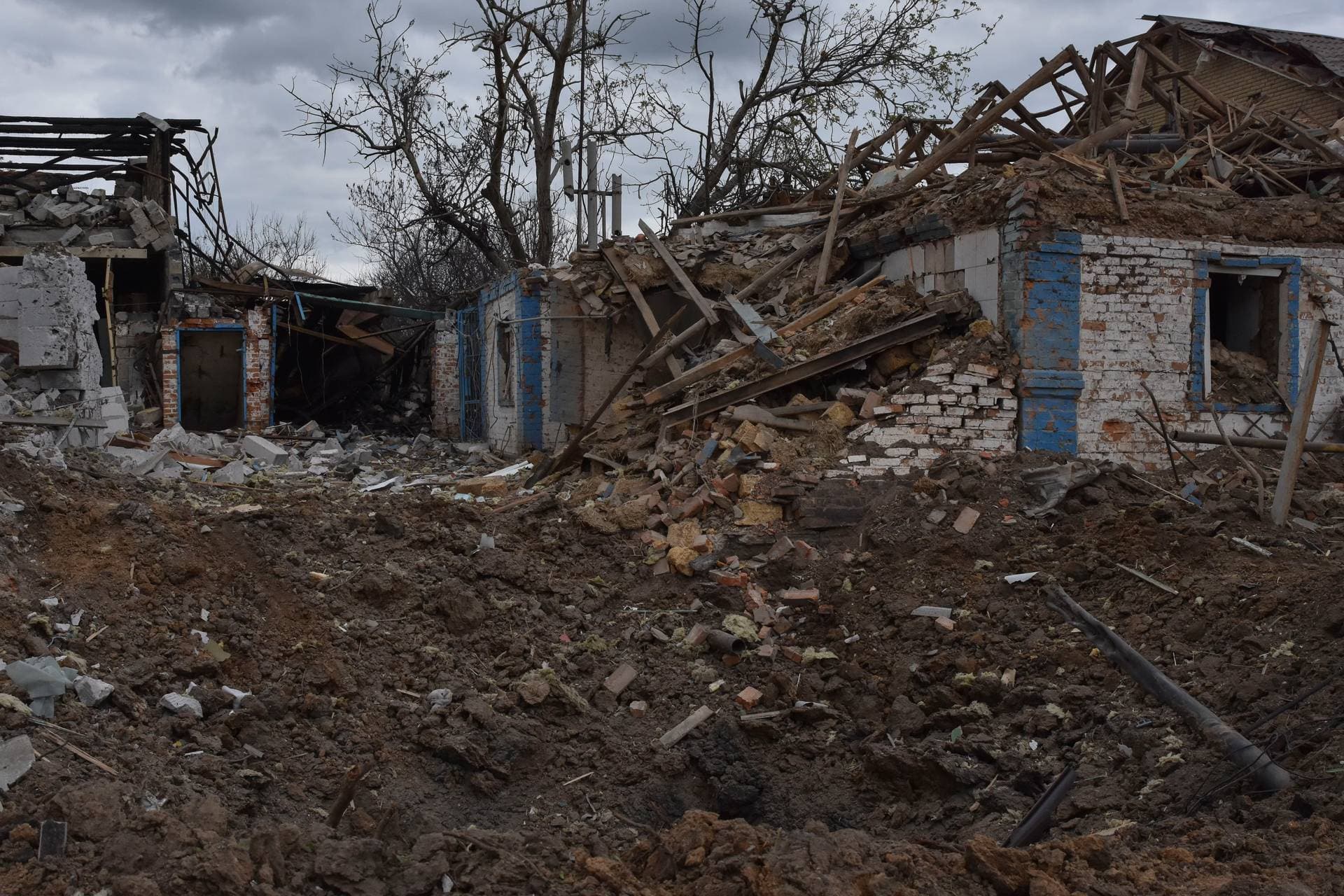 A bomb crater is seen against the background of the houses damaged in a Russian air raid in Orihiv