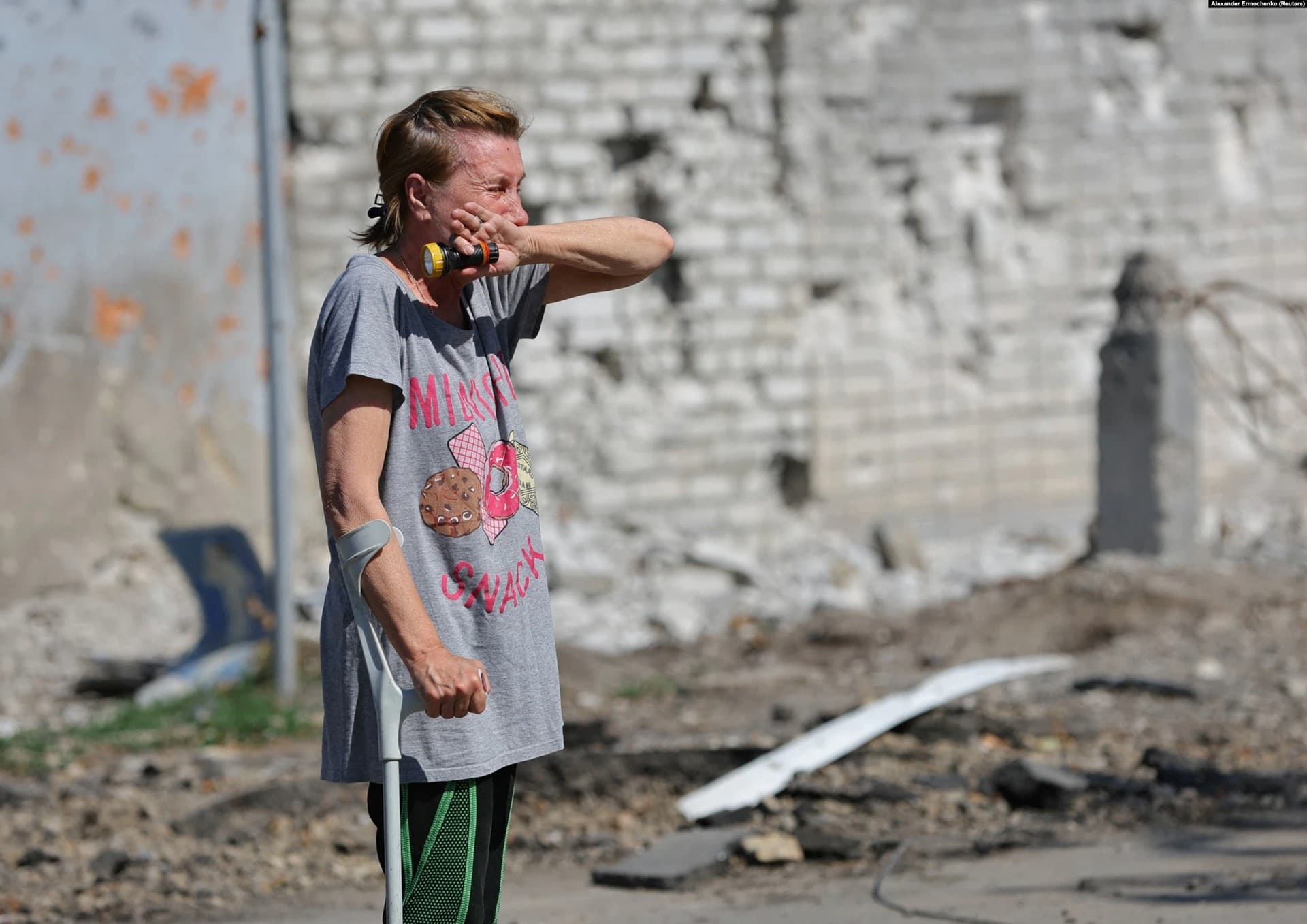 A woman breaks down in front of her destroyed apartment building