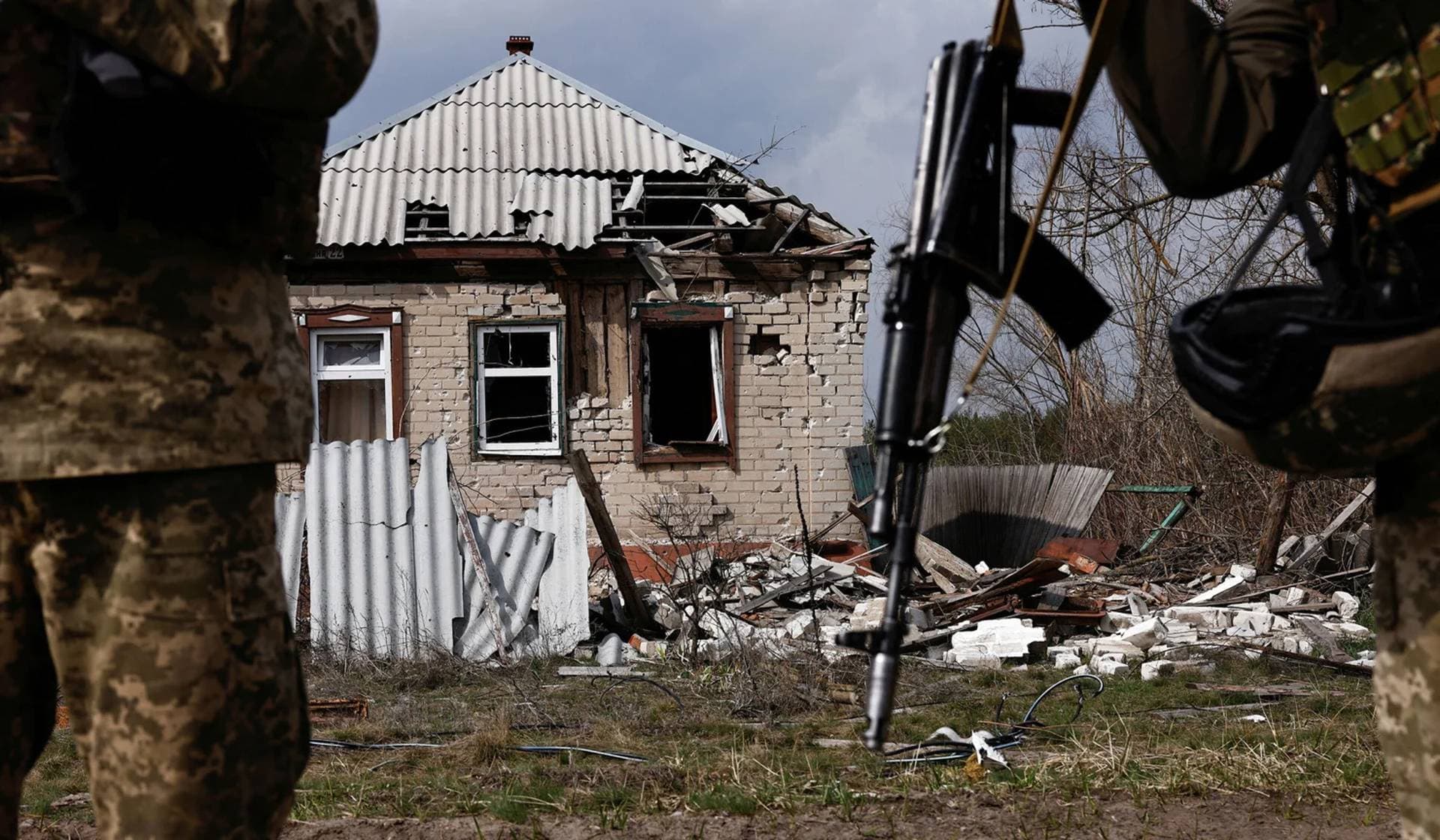Ukrainian servicemen stand next to a destroyed building near the frontline town of Kreminna
