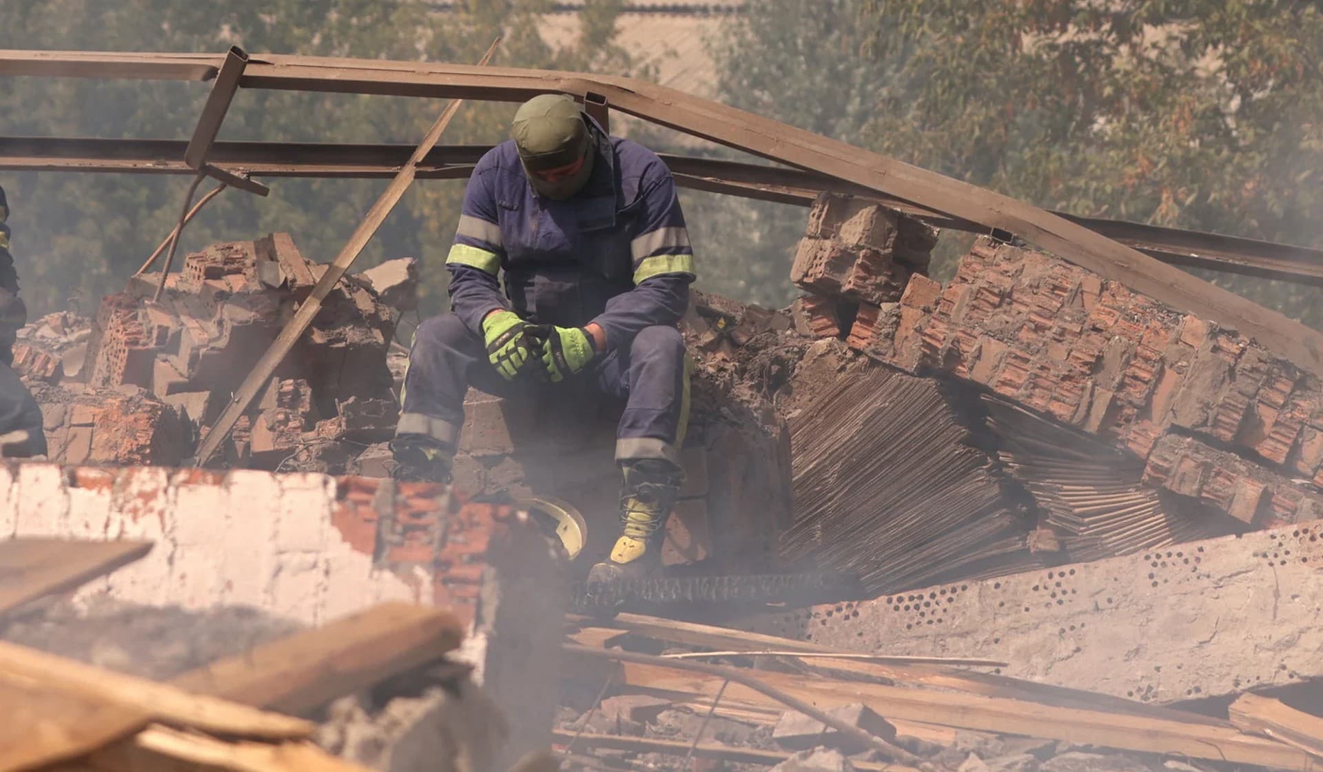 A Ukrainian firefighter takes rest in a factory destroyed by a Russian strike in the city of Slovyansk