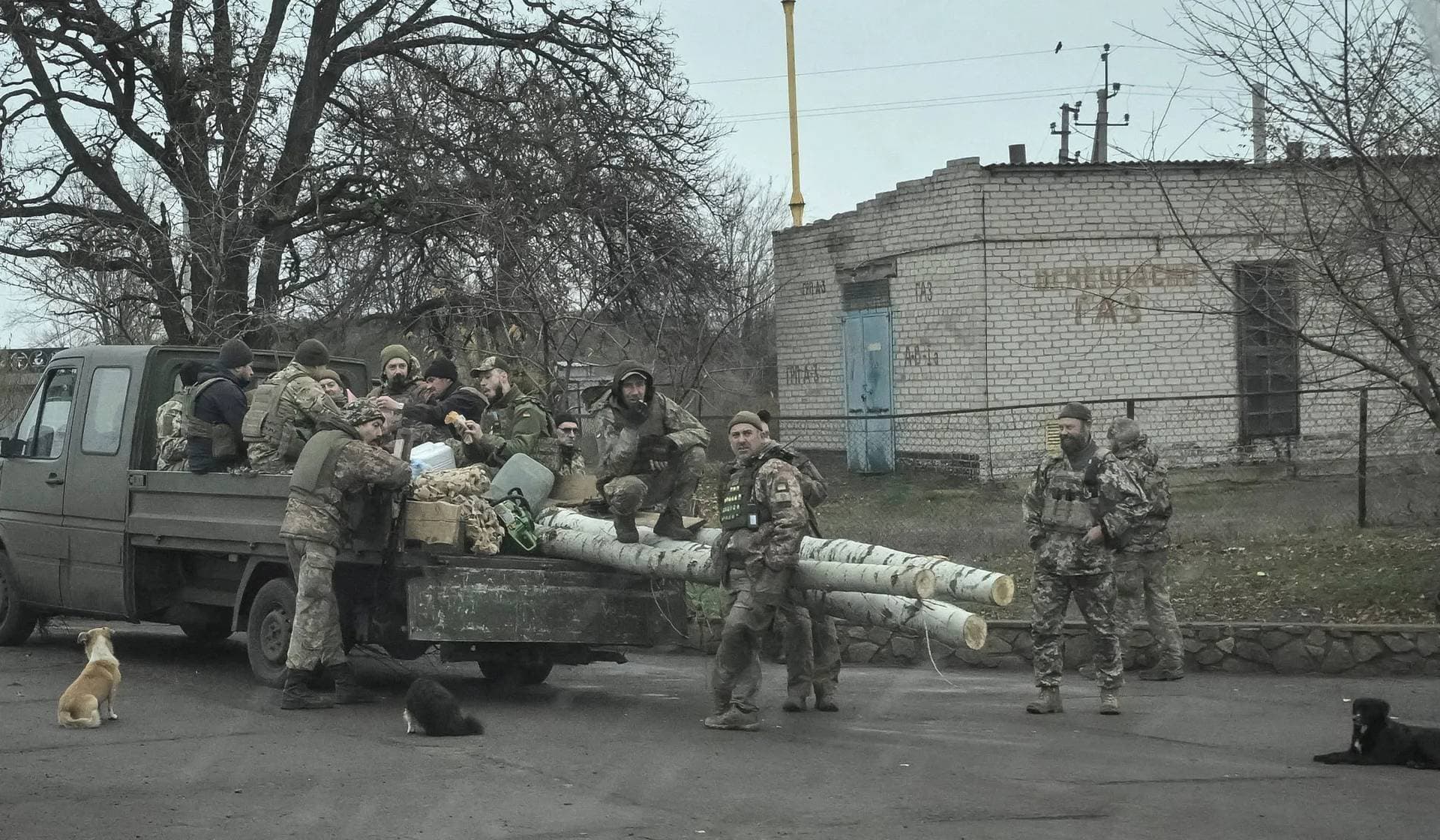 Ukrainian servicemen gather near a vehicle, seen through a window, near the frontline town of Pokrovske