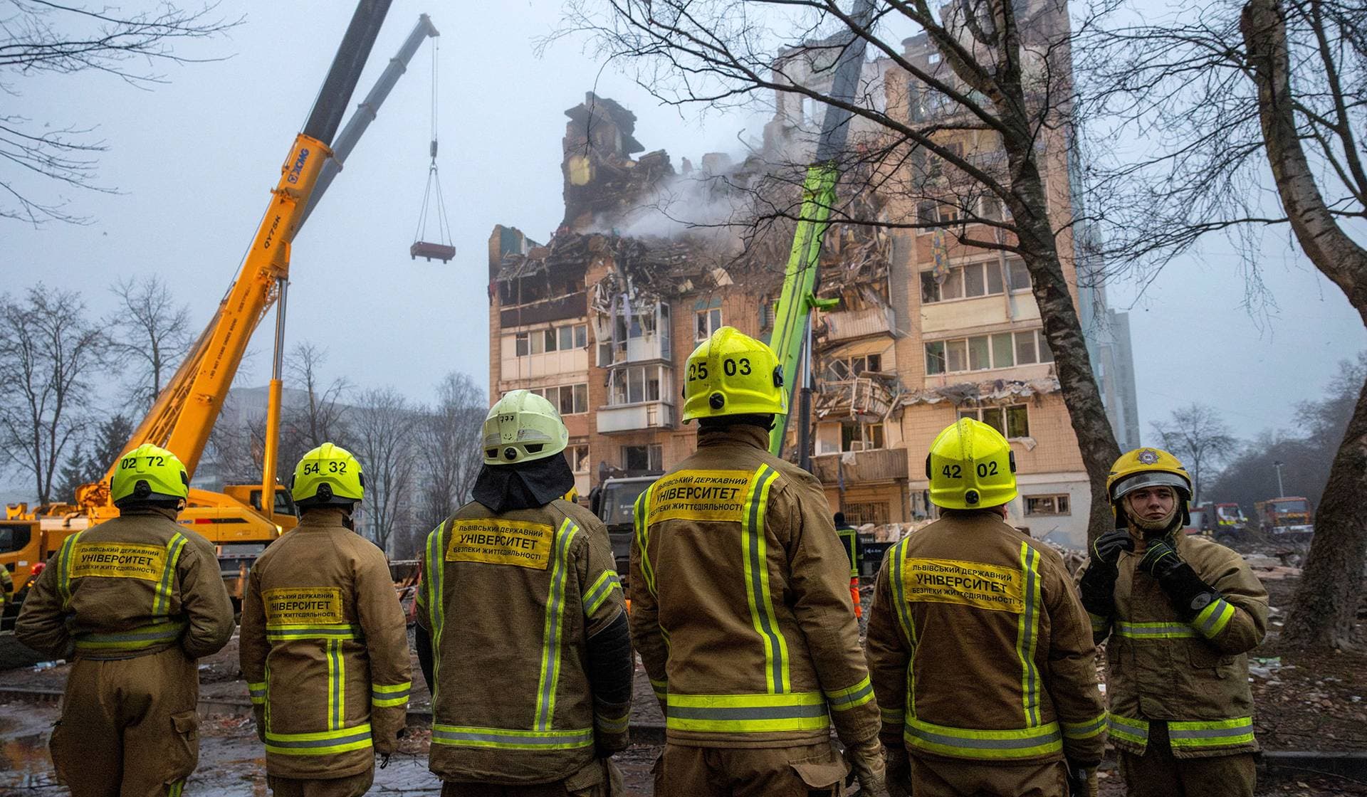 Students preparing to be firefighters gather in front of an apartment building that was hit yesterday by a Russian missile in Ternopil