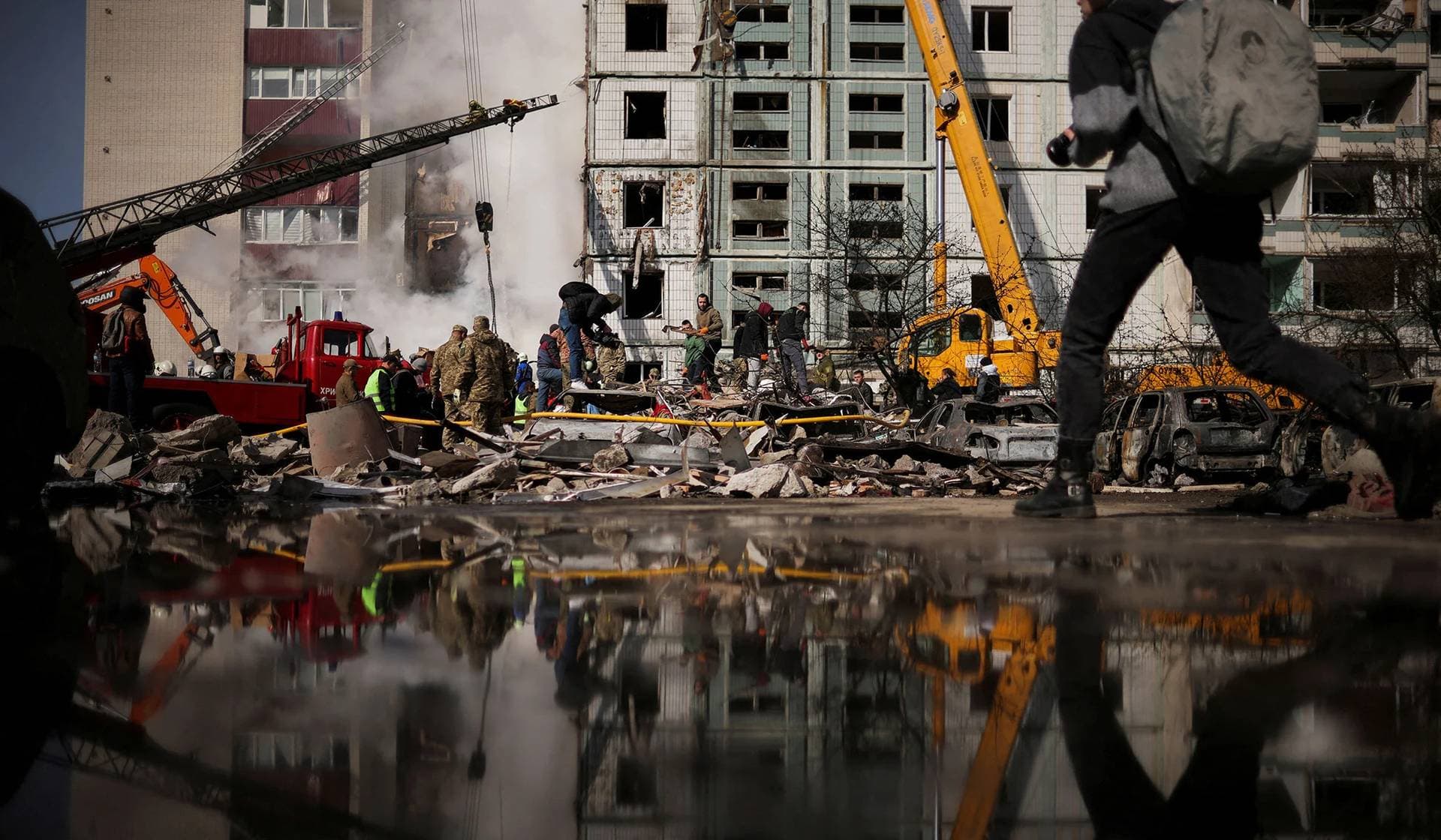 Local residents and rescuers stand amidst the rubble at the site of a heavily damaged residential building hit by a Russian missile in Uman