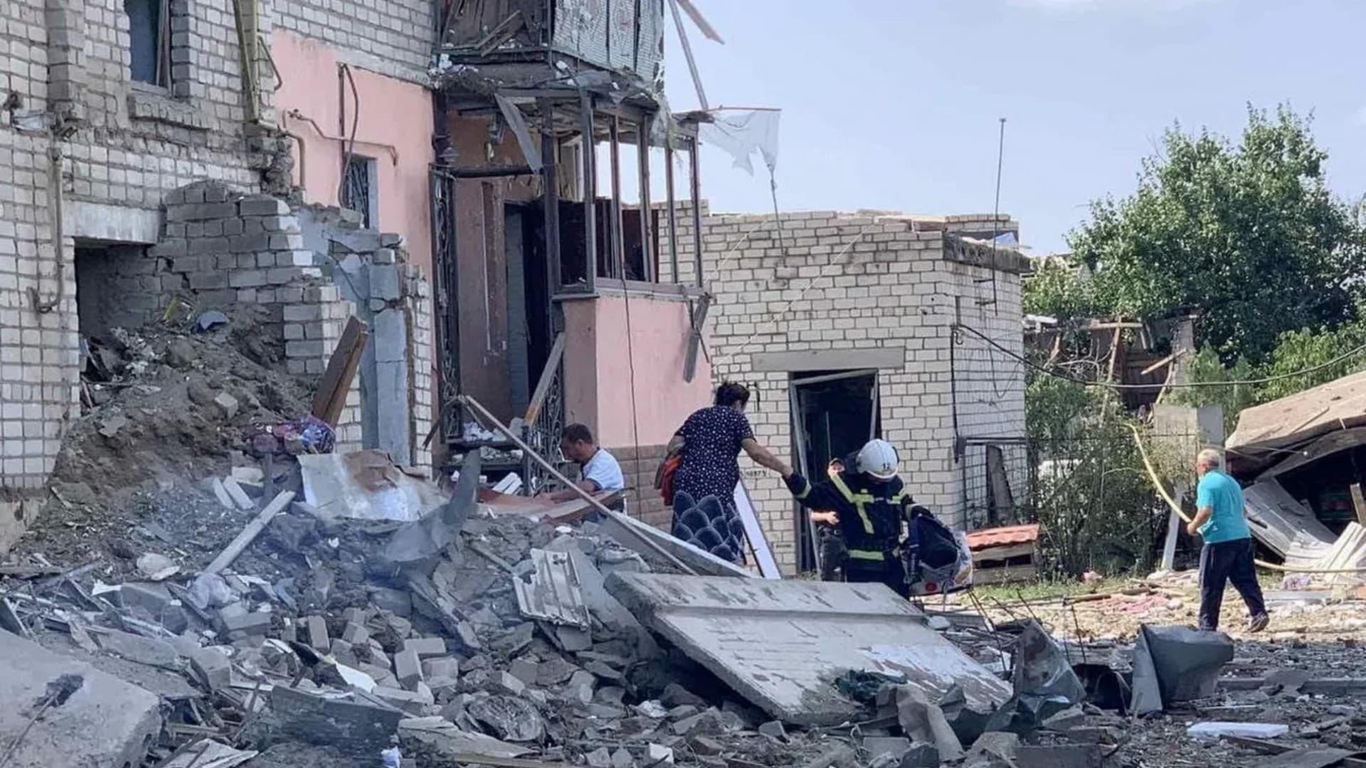 A rescuer helps a woman evacuate a residential building damaged by a Russian missile strike in Voznesensk