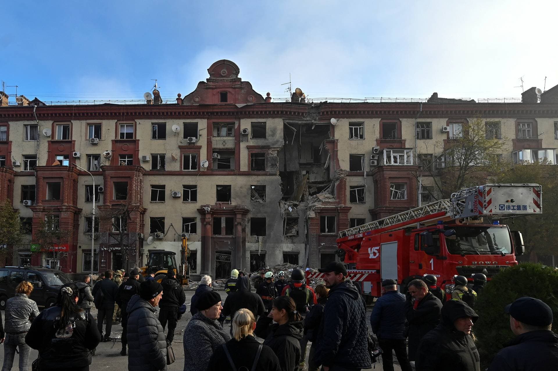 Local residents stand in front of a residential building damaged by a Russian missile strike in Zaporizhzhia