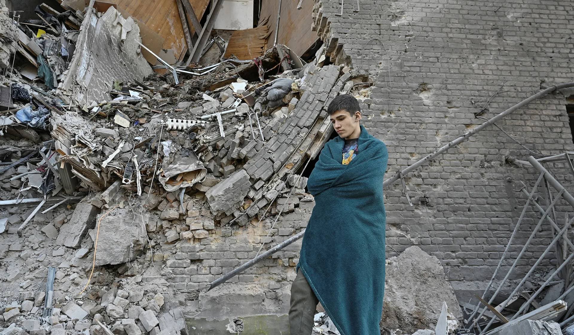 Vladyslav stands next to his apartment destroyed by a Russian air strike in Zaporizhzhia