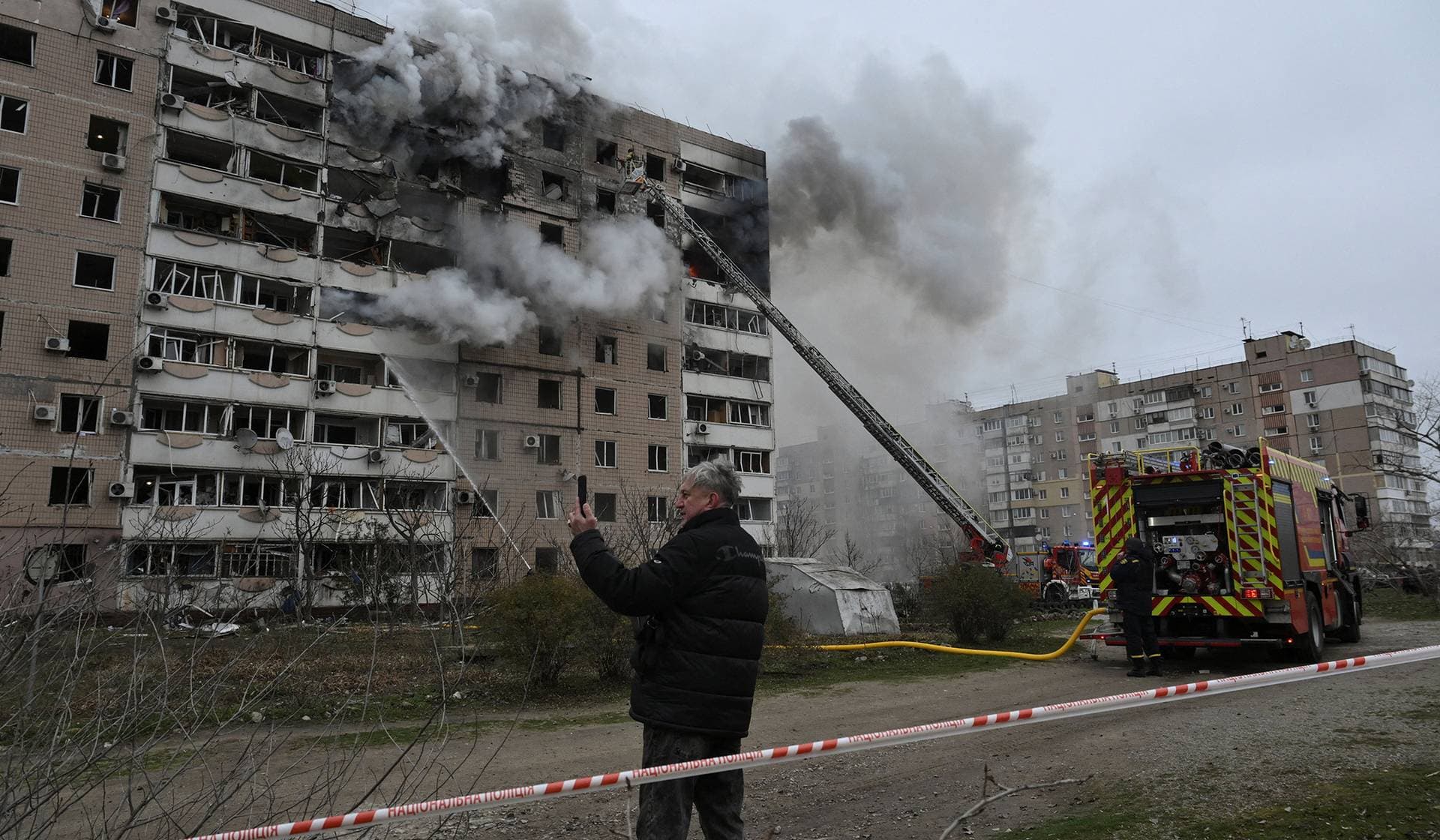 A resident records images on a mobile phone of a burning apartment building, which was hit by a Russian air strike in Zaporizhzhia