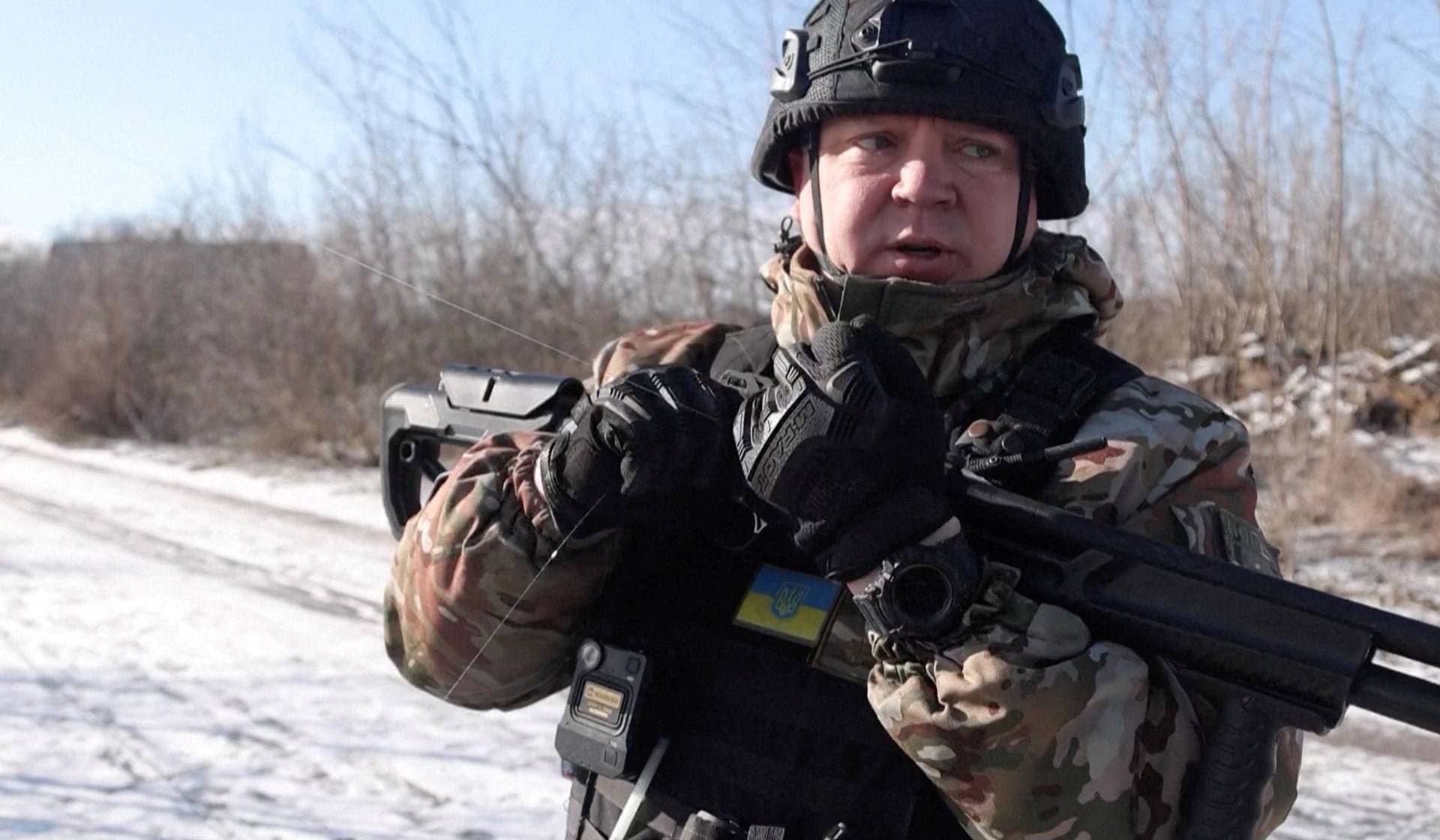 A Ukrainian national police officer, holding a shotgun used as a counter-drone weapon, holds a drone fibre-optic cable during an evacuation of residents from Tavriiske and Yurkivka villages in Ukraine's Zaporizhzhia region