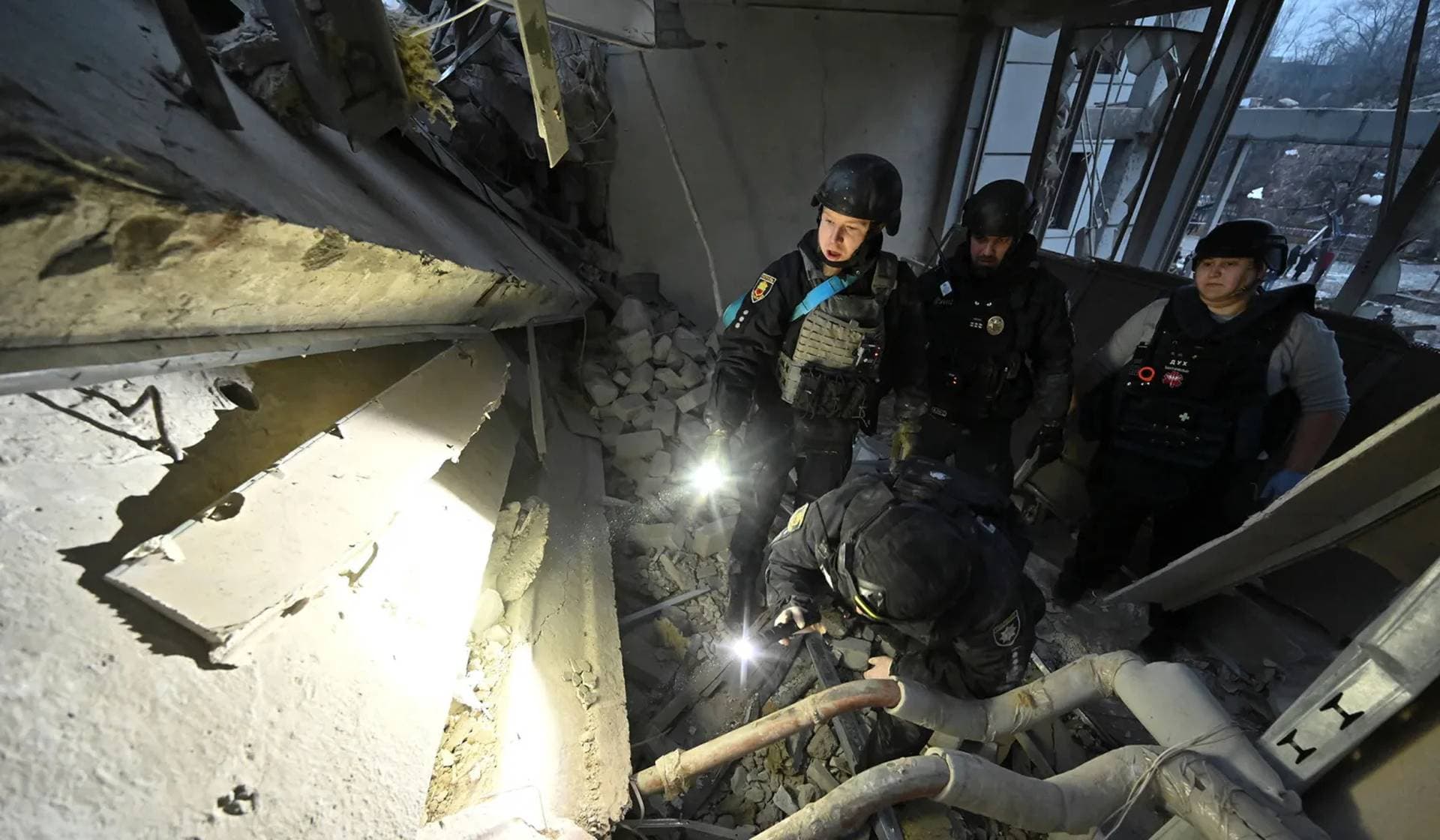 Police officers search for people in the rubble of a building heavily damaged by a Russian missile strike in Zaporizhzhia