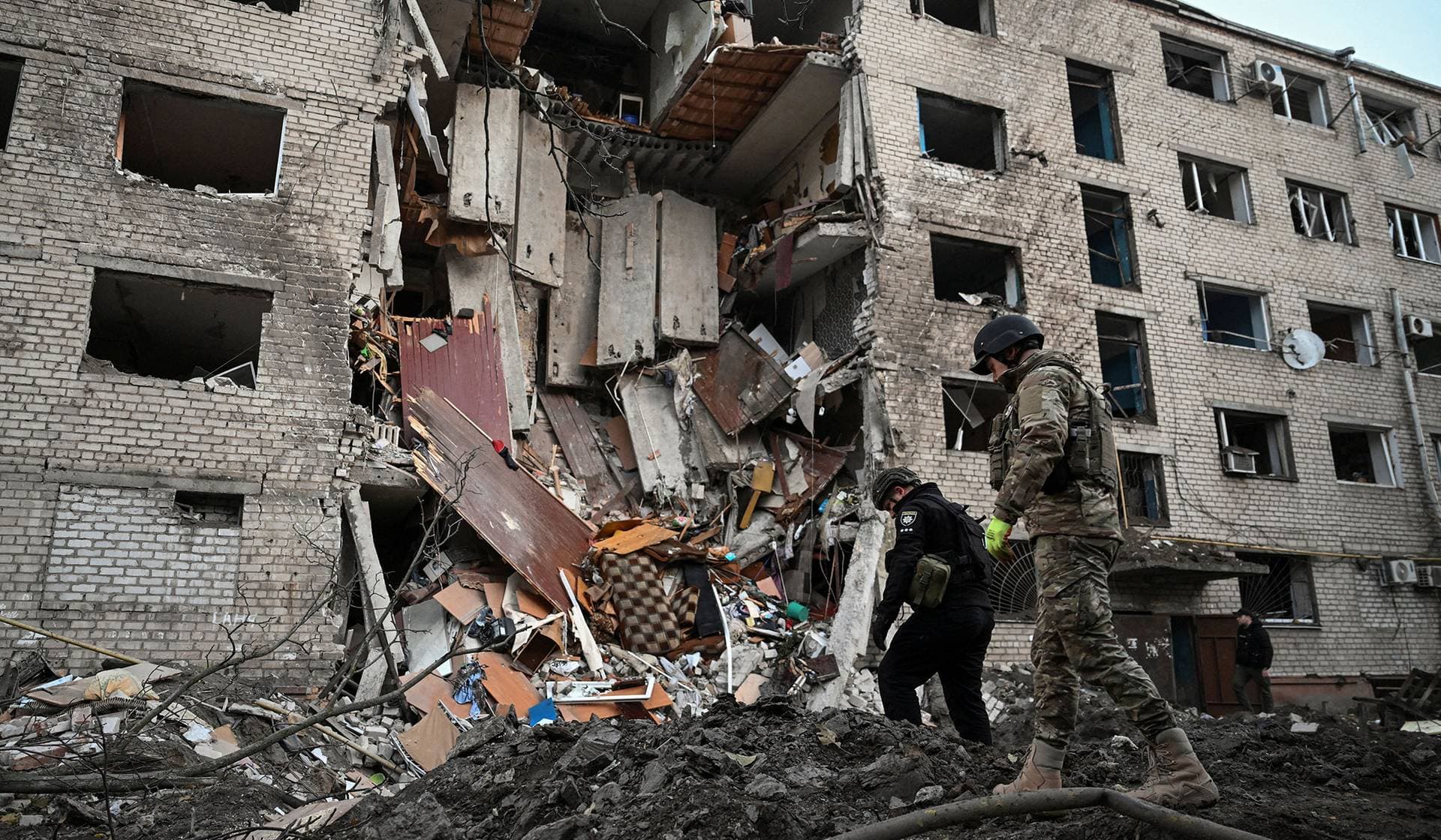 Police investigators inspect debris at a site of a dormitory building heavily damaged during an overnight Russian missile and drone strikes in Zaporizhzhia