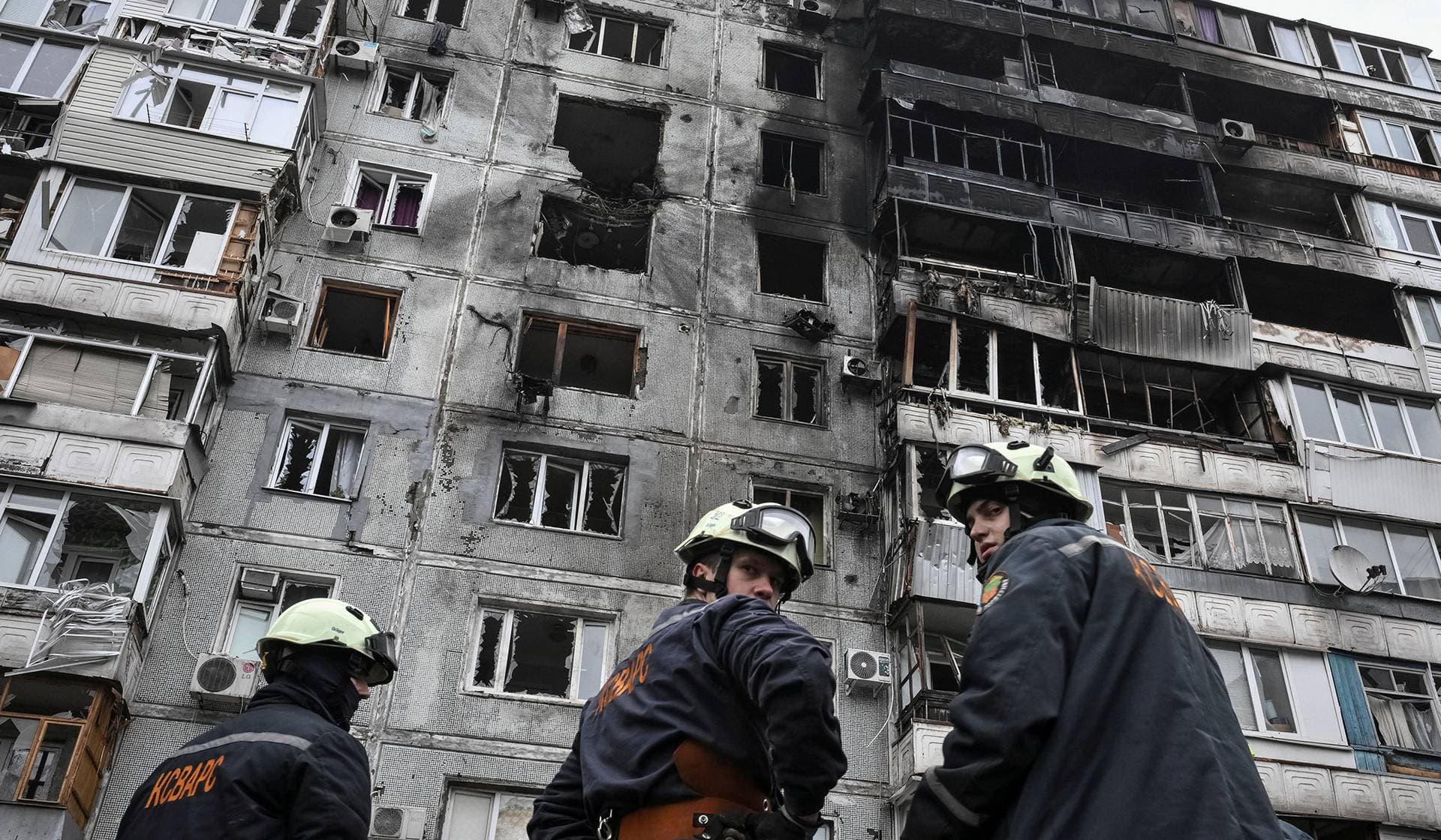 Rescuers stand near the apartment building hit by a Russian drone strike in Zaporizhzhia