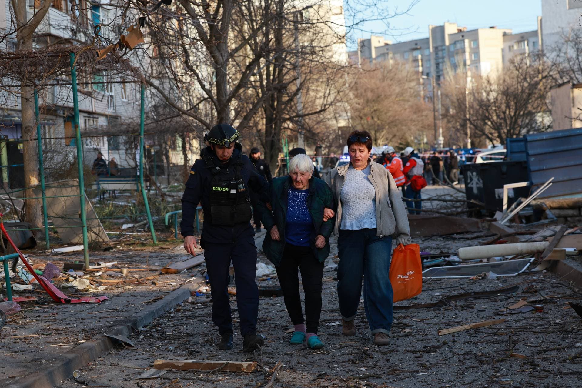 A rescuer helps an elderly woman to leave her home damaged by Russian aerial guided bomb in Zaporizhzhia