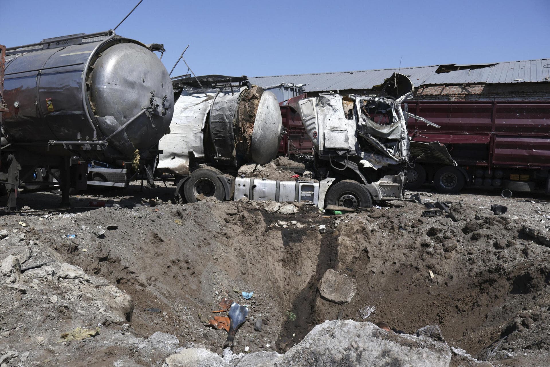 A crater is seen next to destroyed trucks after Russian shelling in Rozumivka