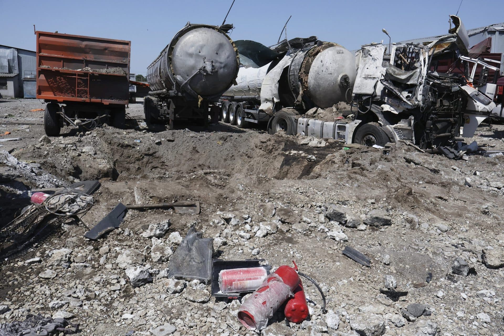 A crater is seen next to destroyed trucks after Russian shelling in Rozumivka