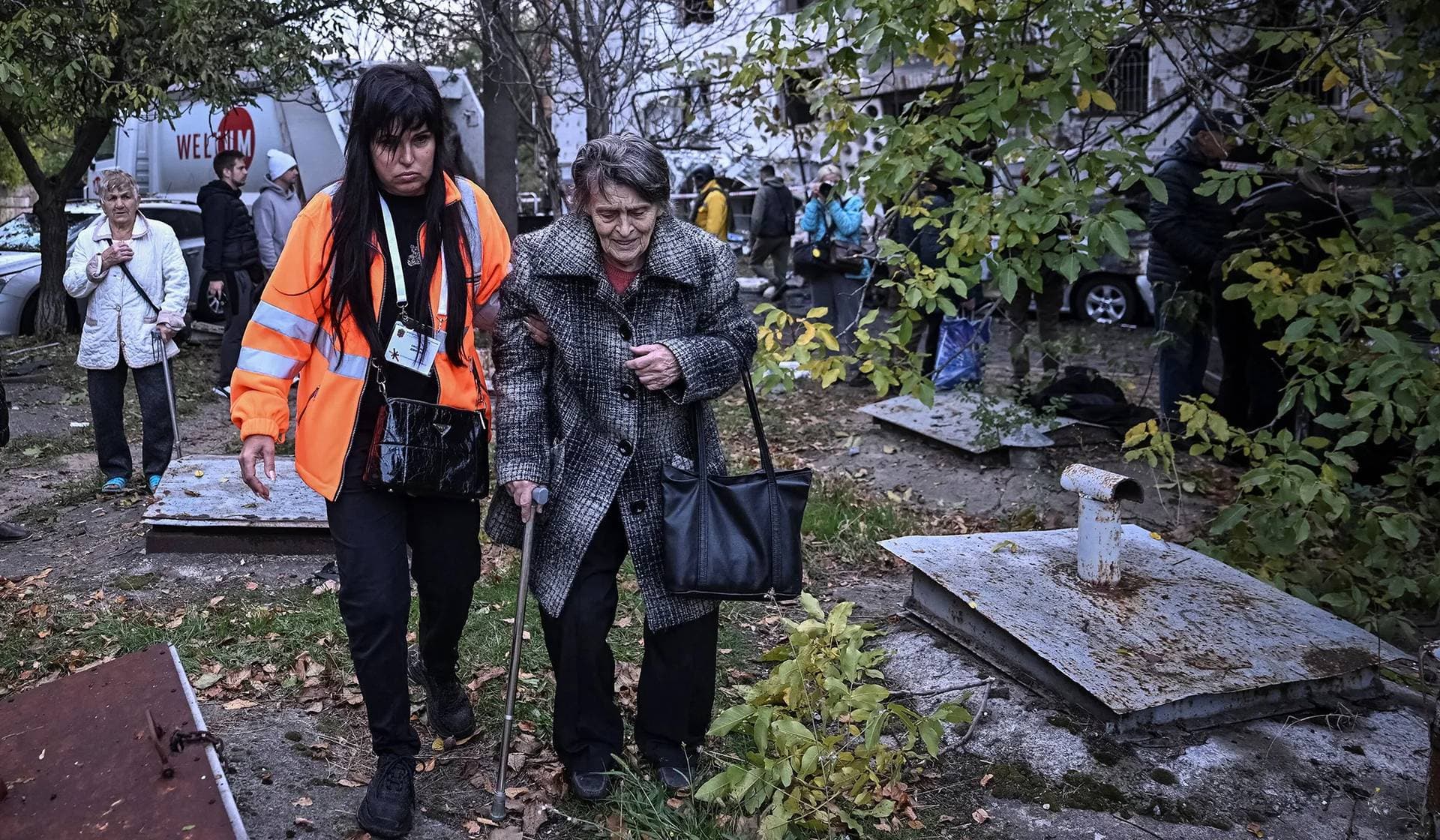 A psychologist assists a resident as they walk near her apartment building damaged by a Russian drone strike in Zaporizhzhia