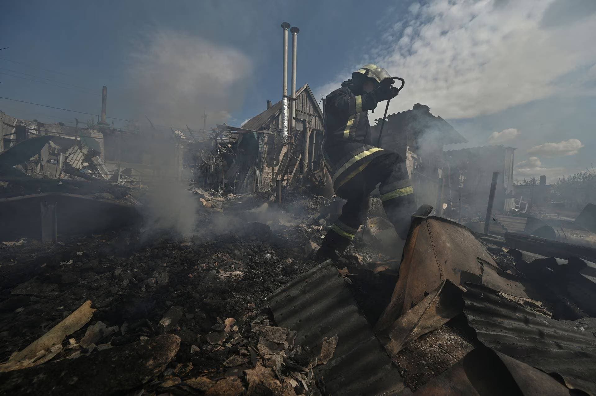 A firefighter works at a site of a residential house destroyed by a Russian military strike in the village of Malokaterynivka