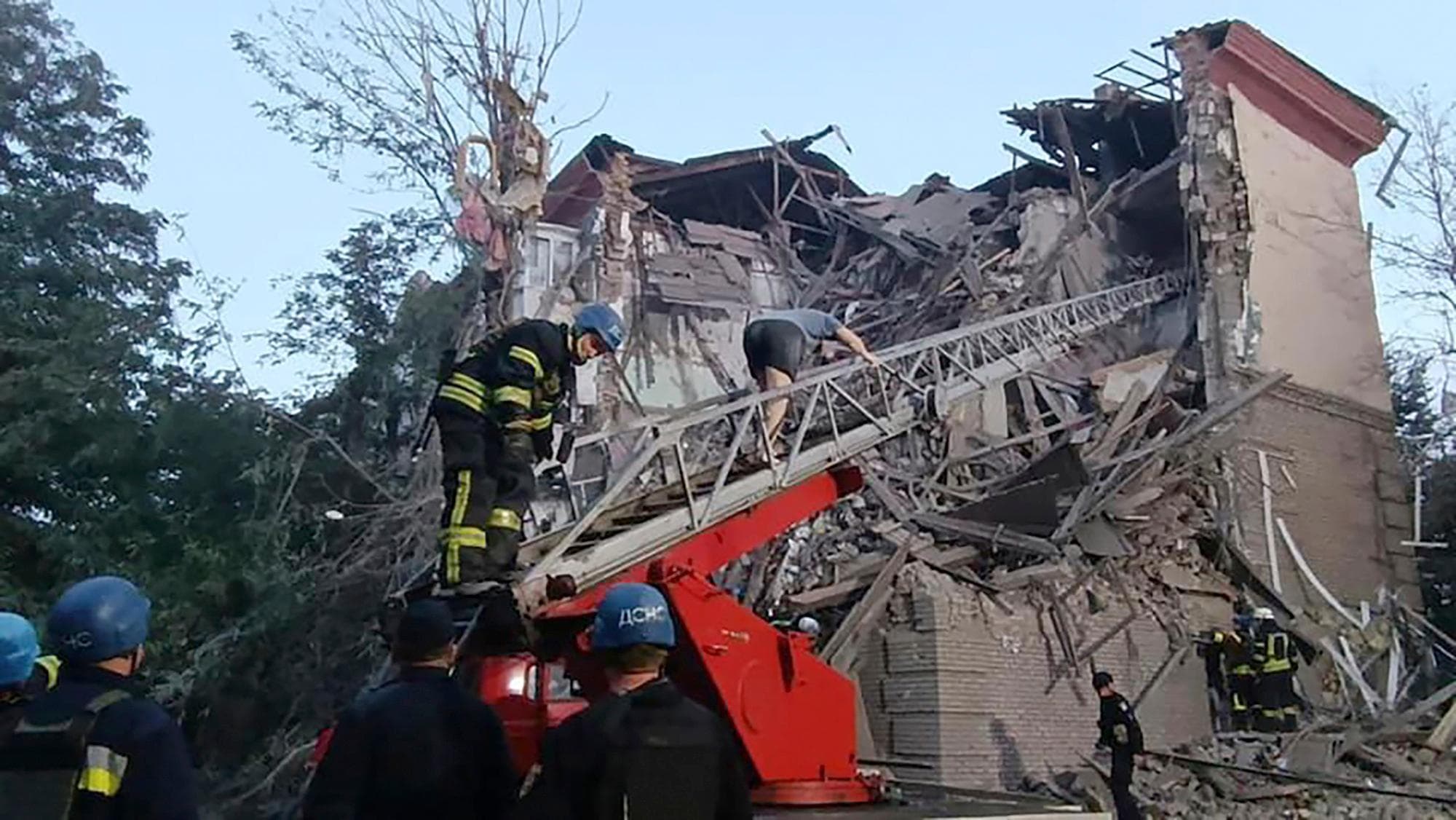 rescuers work on a scene of building damaged by shelling in Zaporizhzhia
